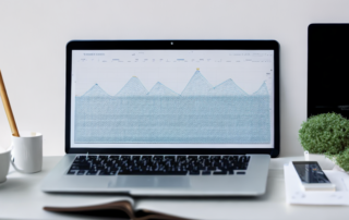 digital planner und laptop auf aufgeraeumtem schreibtisch mit keyword planung und forschung, diagramme und grafiken fuer datenbasierte methoden